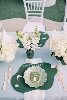 the table is set with white flowers and green plates