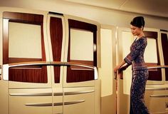 a woman is standing in an airplane looking at the back door and holding a suitcase