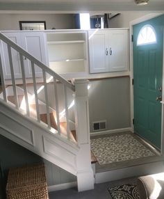 a staircase leading to a green door in a house with white stairs and wooden handrails