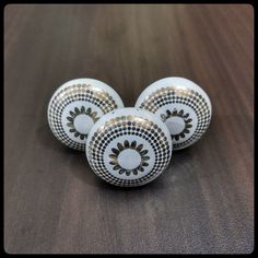 three white and gold decorative knobs sitting on a table top with black dots in the center