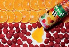 oranges and raspberries are next to a can of soda with liquid on it