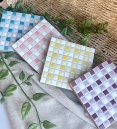 three different colored glass tiles sitting on top of a table next to a wicker basket