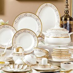 a table topped with lots of white and gold dishes