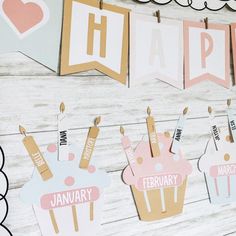 some cupcakes are hanging from clothes pins on a wooden wall with happy birthday banners