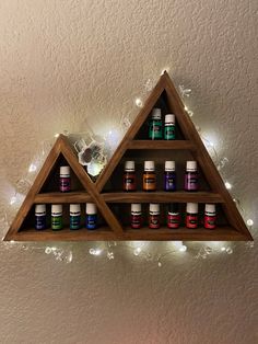 a wooden shelf filled with bottles of essential oils on top of a wall next to a candle