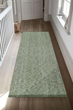 a green rug on the floor in front of a white door