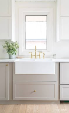 a white kitchen sink sitting under a window in front of a counter top with drawers