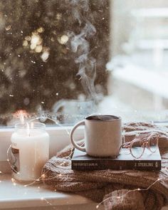 a cup of coffee sitting on top of a window sill next to a book