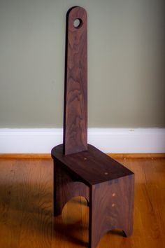 a wooden chair sitting on top of a hard wood floor next to a white wall