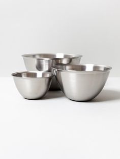 three metal bowls sitting next to each other