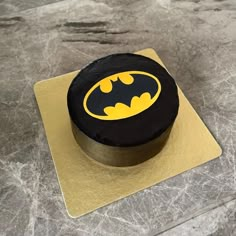 a black and yellow cake with a batman symbol on it sitting on a gold plate