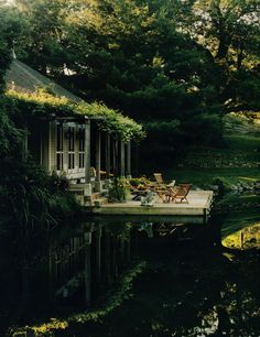 a house sitting on top of a lake next to a lush green forest