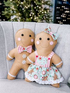 two gingerbread dolls are sitting on a couch in front of a christmas tree with lights