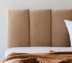 a bed with two pillows on top of it and a blanket over the headboard