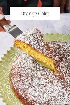 a person cutting into a cake on top of a green plate with powdered sugar