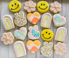 decorated cookies arranged in the shape of rainbows, hearts, and flowers on a wooden surface