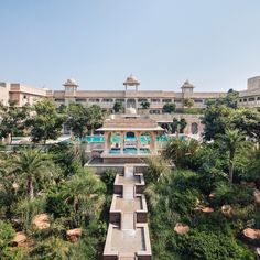 an aerial view of a large building surrounded by palm trees and other greenery in the foreground