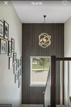 a hallway with pictures on the wall and a chandelier hanging from the ceiling