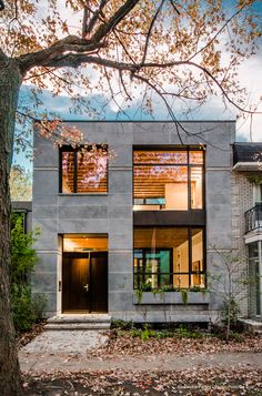 a modern house with large windows and lots of leaves on the ground in front of it