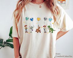 a woman wearing a t - shirt with cartoon characters on it and balloons in the air