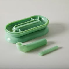 a green plastic container with three toothbrushes in it and two other items next to it