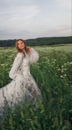 a woman in a white dress is walking through tall grass