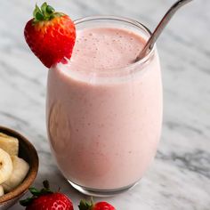 a strawberry smoothie in a glass next to sliced bananas