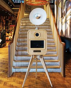 a camera sitting on top of a tripod in front of a stair case with a light above it