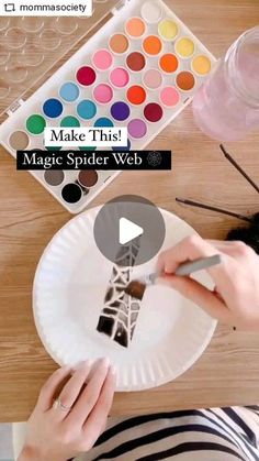 a person is painting a paper plate with watercolors on it and the words make this magic spider web