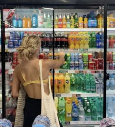 a woman in a yellow bra top is shopping for drinks and sodas at a grocery store