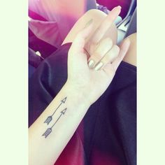 a woman's arm with an arrow tattoo on it and a cell phone in her hand