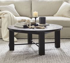 a living room with a couch, coffee table and candles on the tables in front of it