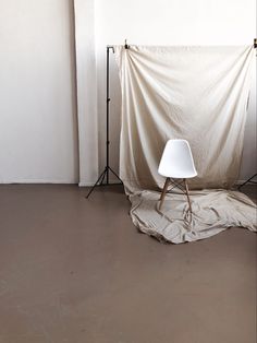 a white chair sitting on top of a hard wood floor next to a light stand