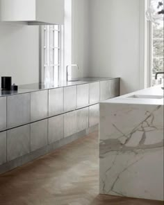 a white kitchen with marble counter tops and cabinets in the corner, along with a large window