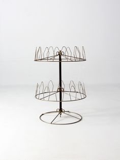 a three tiered metal stand with wire on it's sides and circular base