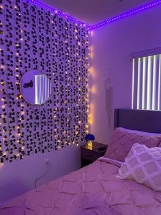 a bed room with a neatly made bed and purple lights on the wall behind it