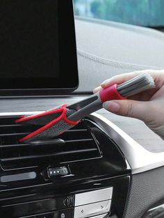 a person holding a brush in their hand while sitting in a car with the radio on