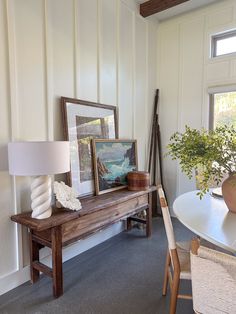 a room with a table, chairs and pictures on the wall