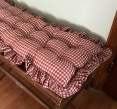 a wooden bench with a red and white checkered blanket on it