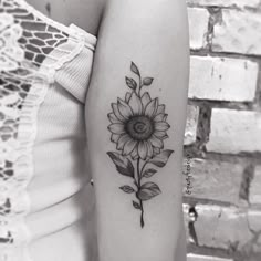 a woman's arm with a sunflower tattoo on it