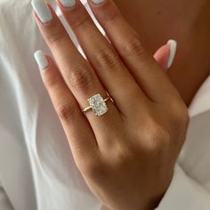 a woman's hand with white manicured nails and a diamond ring