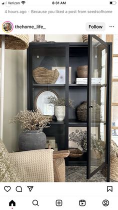 a black bookcase with wicker baskets on top and other decorative items in it