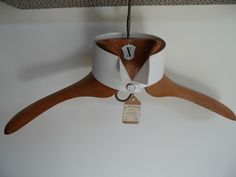 a clock hanging from the ceiling on a wooden hanger with a tag attached to it