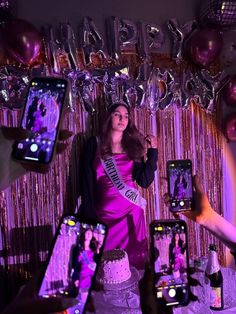 a woman holding up two cell phones in front of her face and surrounded by balloons