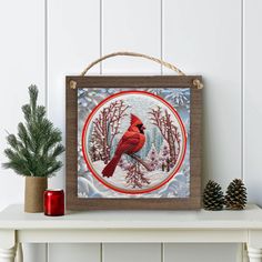 a red cardinal sitting on top of a white table next to a potted plant