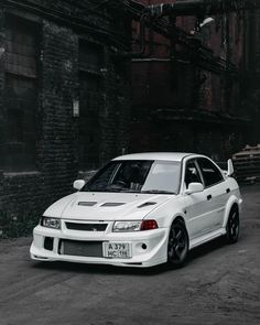 a white car parked in front of an old brick building