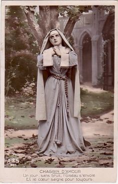 an old photo of a woman dressed as a nun in front of a tree with leaves on the ground