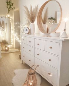 a white dresser topped with lots of drawers next to a wall mounted clock and lights