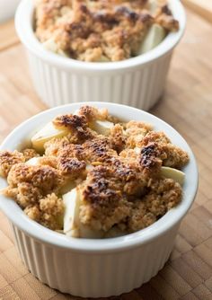 two white bowls filled with food on top of a wooden table