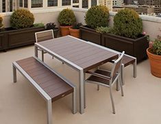 an outdoor table and benches on a roof with potted plants in the foreground